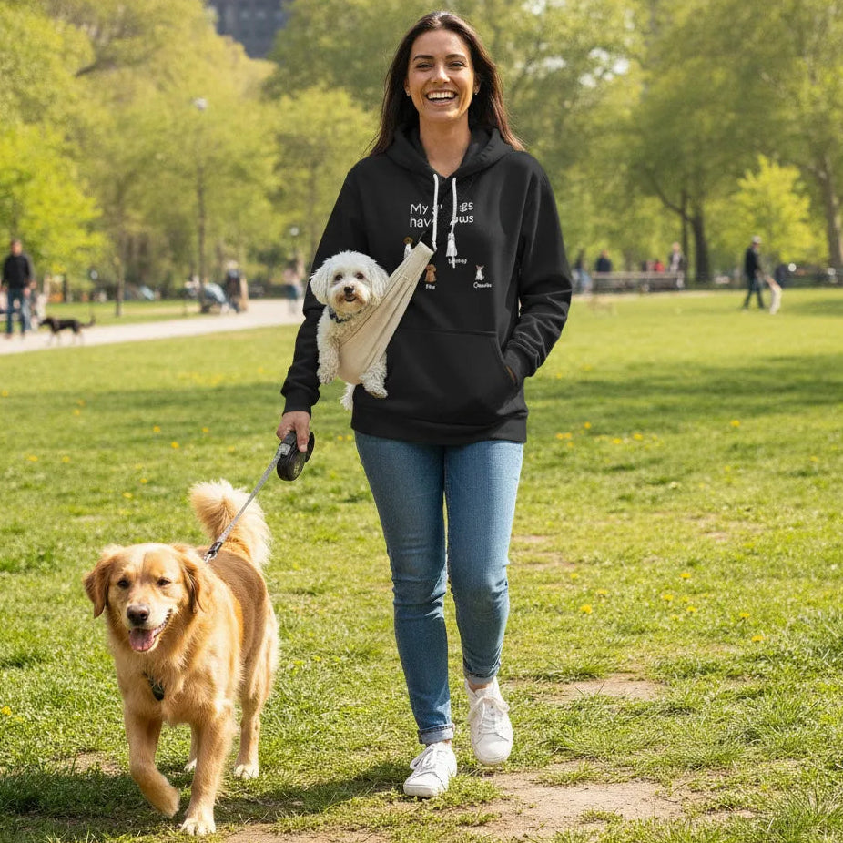 Woman wearing Personalized My Siblings Have Paws Embroidered Hoodie Dogs & Names in Black walking two dogs in a park.
