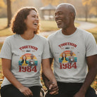 Couple wearing personalized Together Since shirts celebrating their love story. 'Together Since 1984' t-shirts in a park setting.