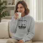Woman wearing a Custom Embroidered Personal Pet 'Stalkers' Adult Unisex Hoodie Pet Dogs & Cats Caricatures Gray hoodie in grey, holding a mug in a living room.