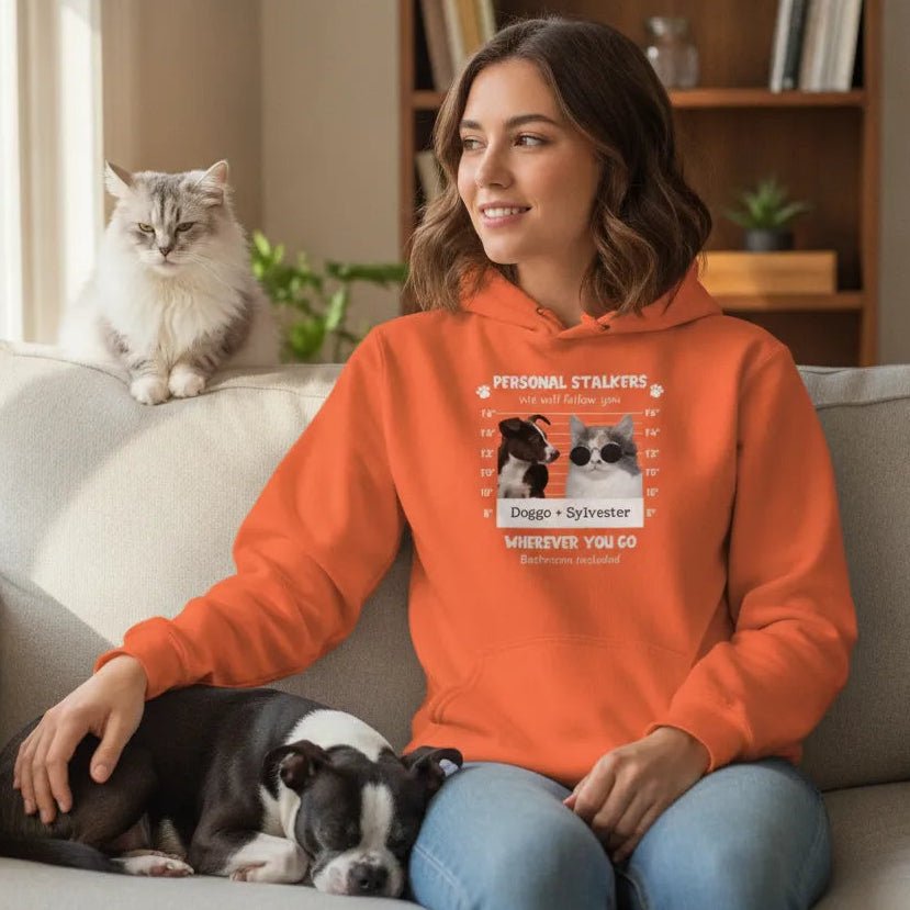 Woman wearing a personalized Pet Stalker hoodie in orange featuring pet photos for dog and cat lovers, sitting with pets.